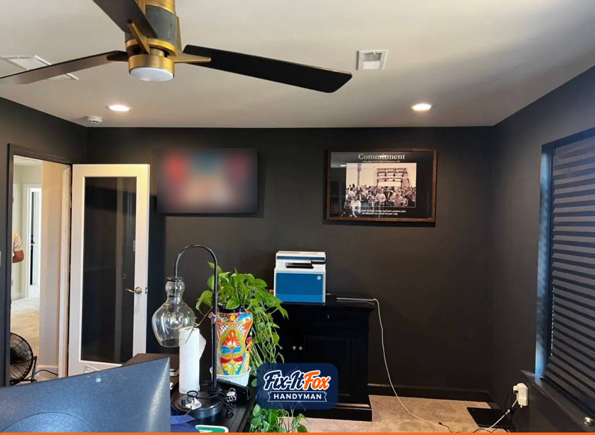 Home office with two large framed pieces hung level on a dark wall