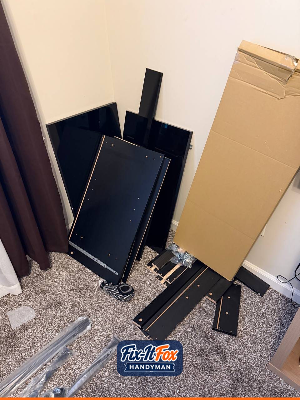 Flat-pack black furniture panels and box leaning in a bedroom corner